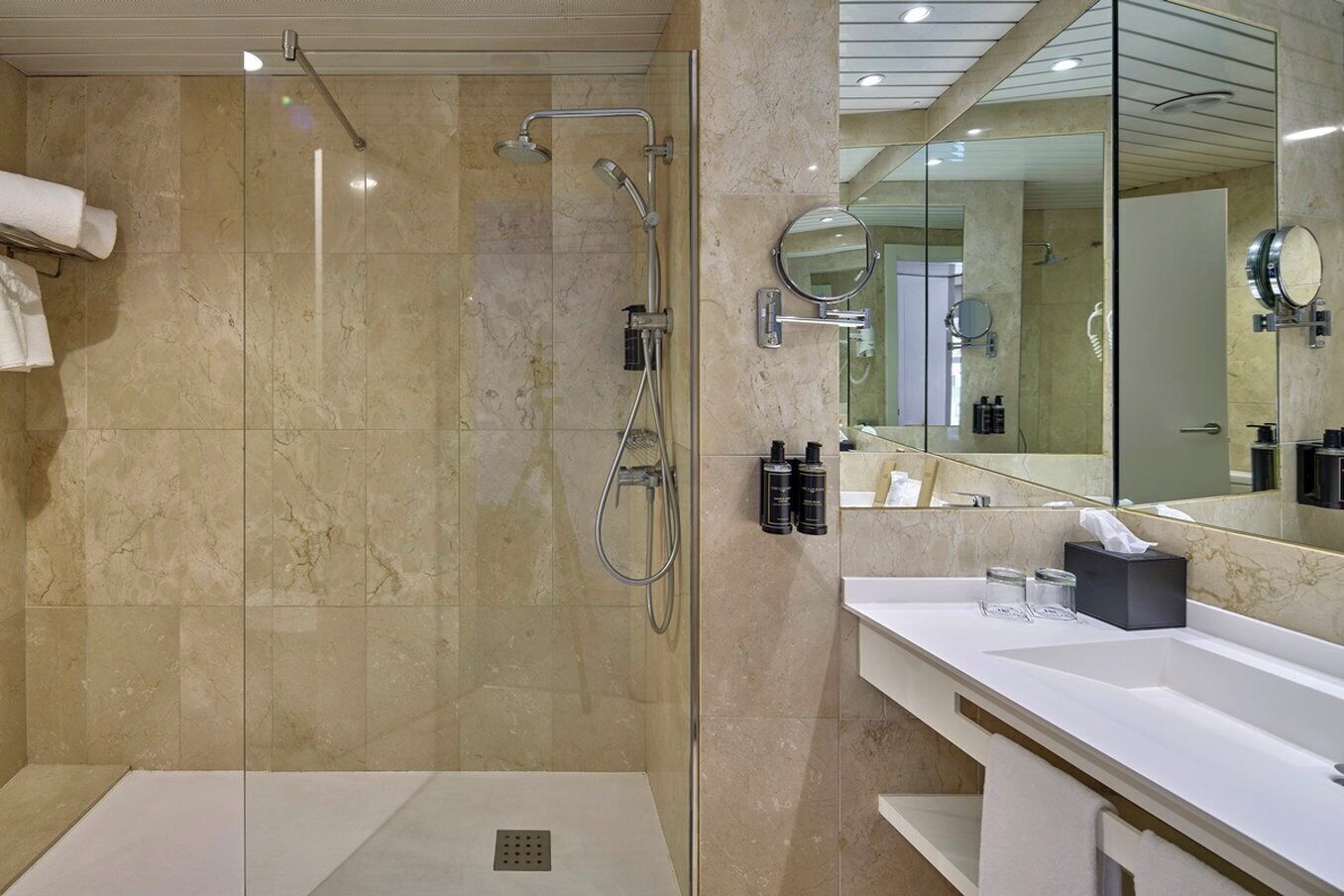 Un baño moderno con ducha de vidrio, un espejo grande y un tocador blanco.
