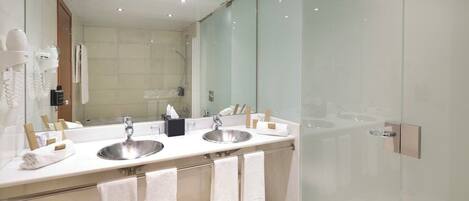 A modern bathroom with two sinks, a large mirror, and a glass shower enclosure.