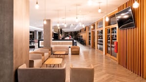 Ein modernes Interieur mit Sofas, Tischen und einem an einer Holzwand befestigten Fernseher.