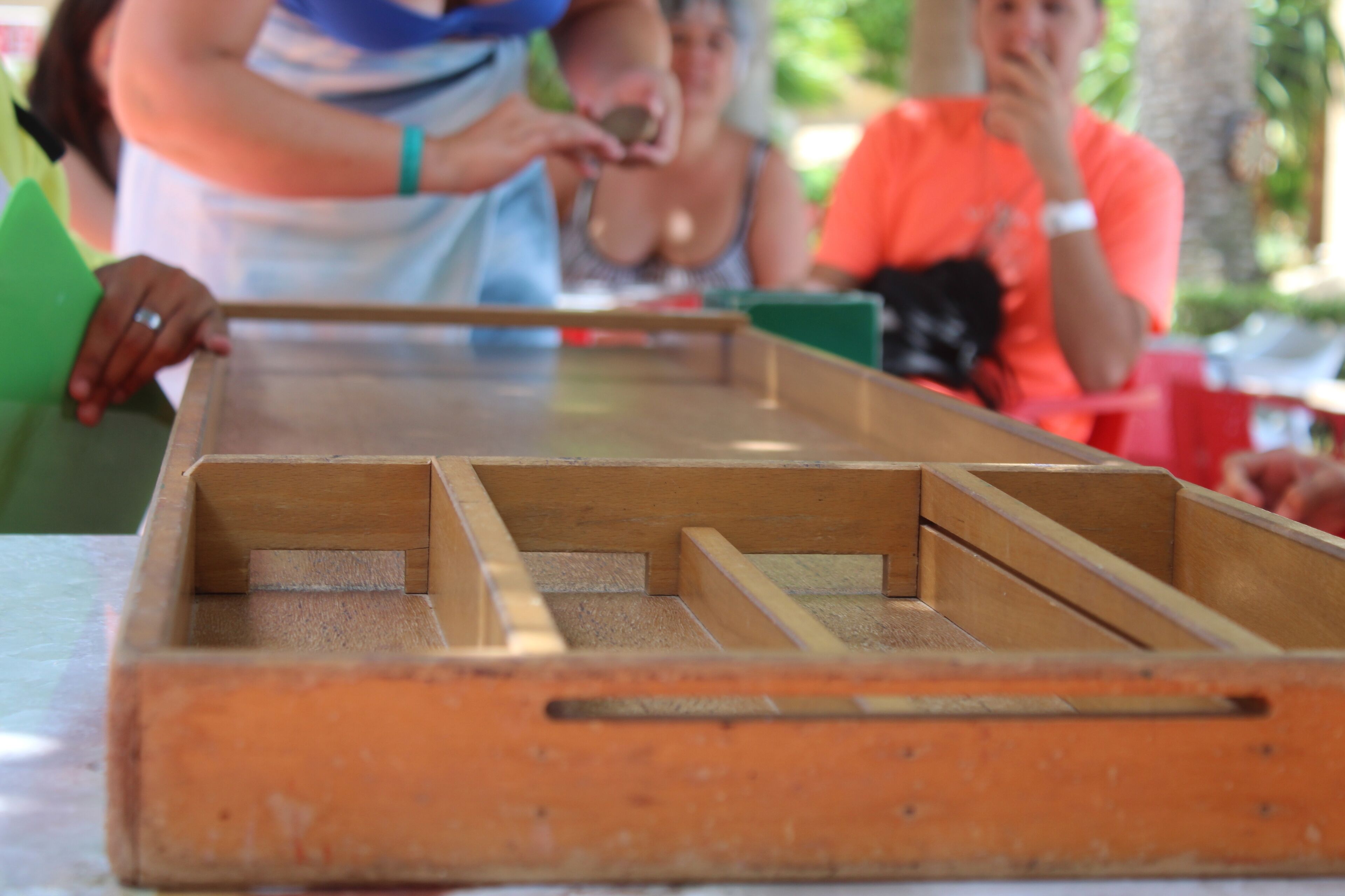A wooden table with multiple compartments, likely used for games or activities.