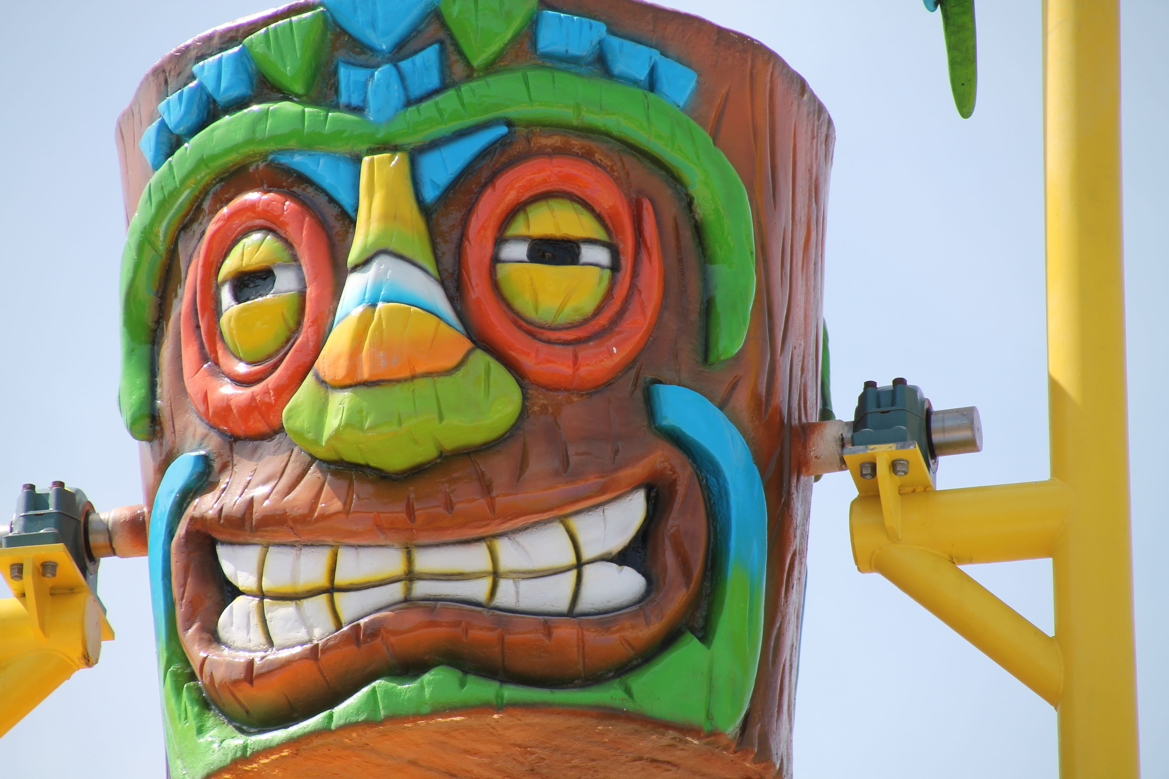 Una gran escultura de madera, colorida y con rostro, posiblemente un tótem o adorno decorativo.