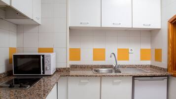 Een keuken met witte kasten, een magnetron, een spoelbak en een vaatwasser.