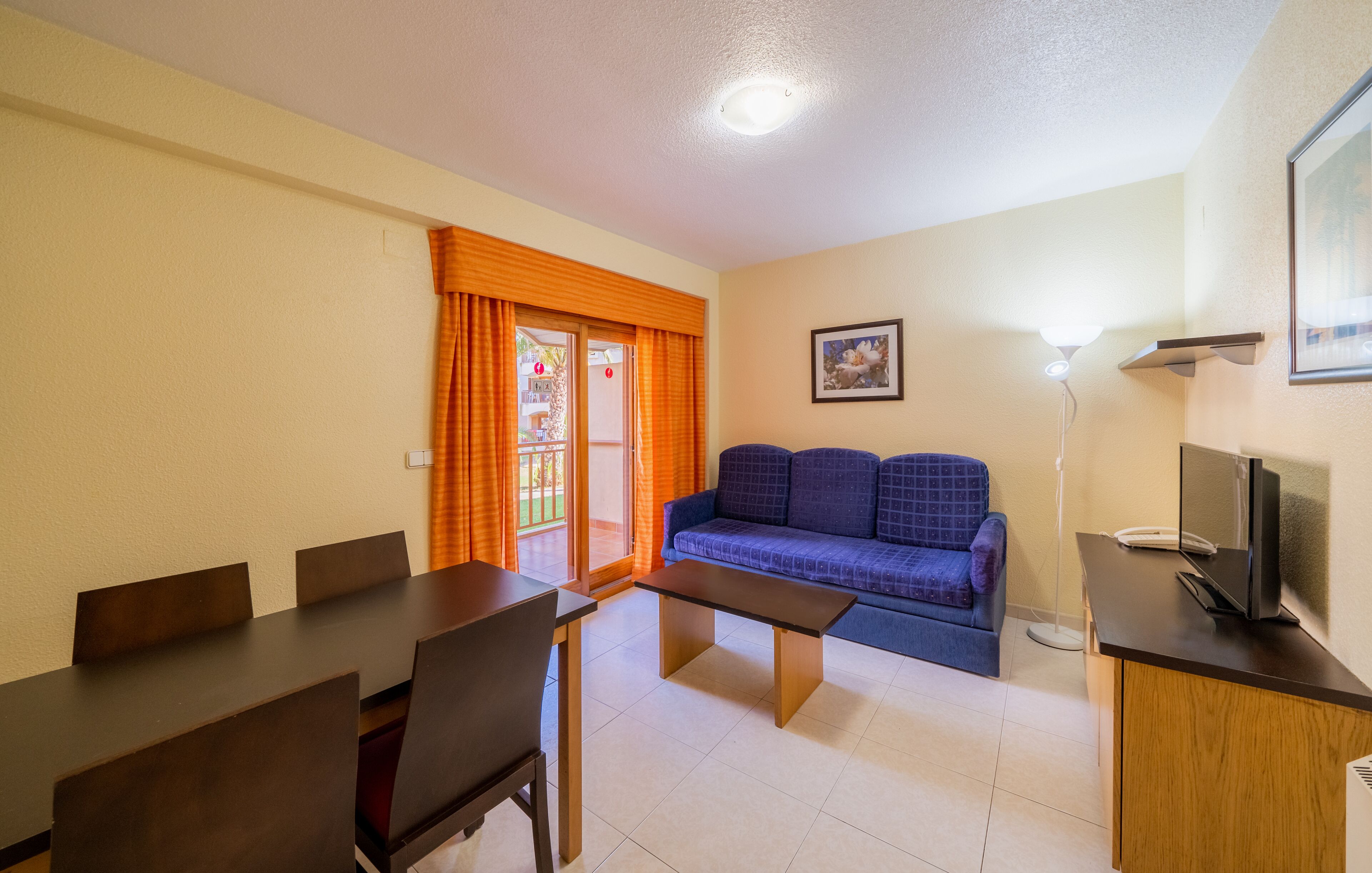 Un espacio habitable compacto con una mesa de comedor, sillas, un sofá y un televisor.