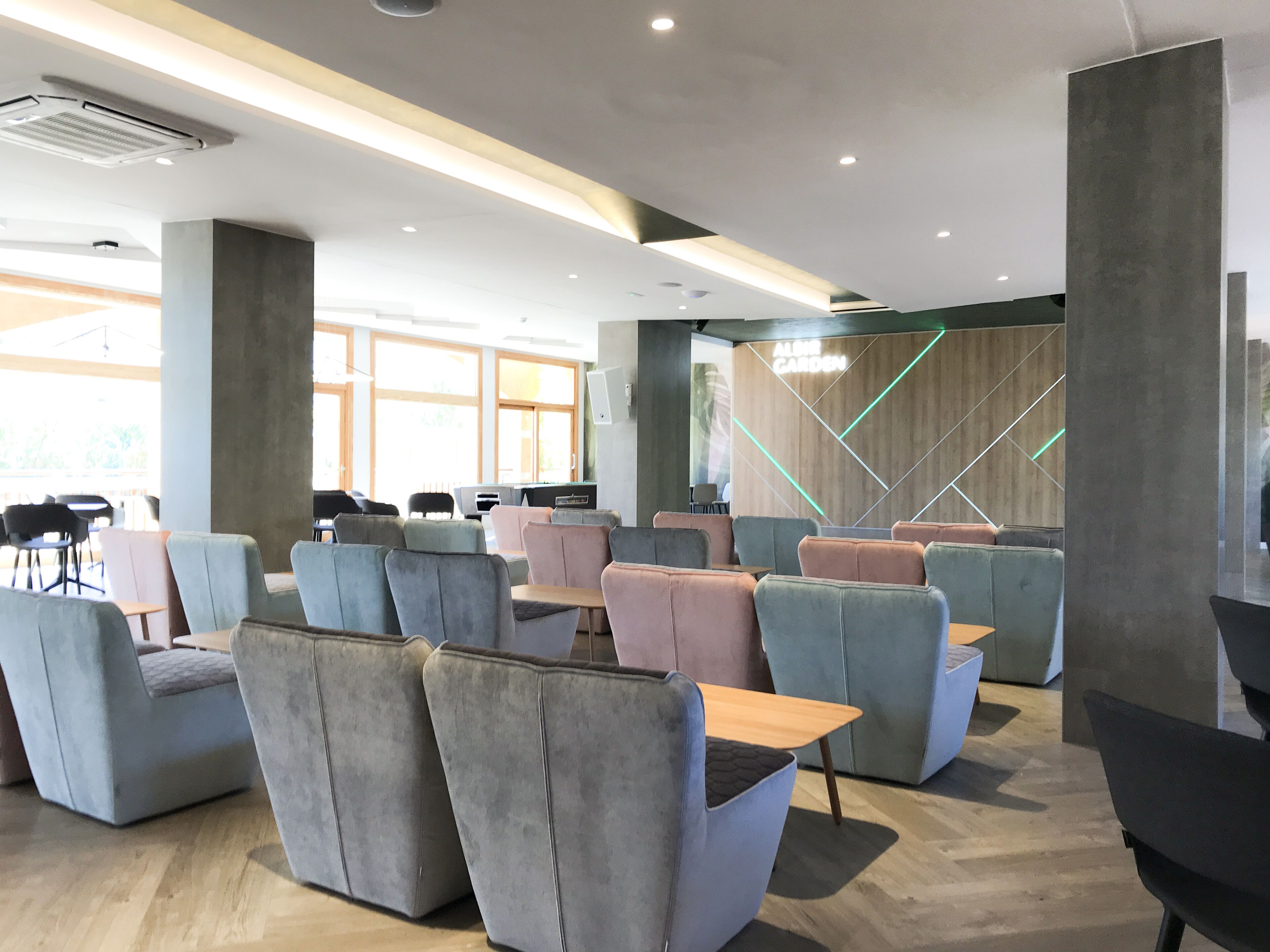 Un espace de détente moderne avec des sièges rembourrés, des tables en bois et un motif géométrique sur le mur.
