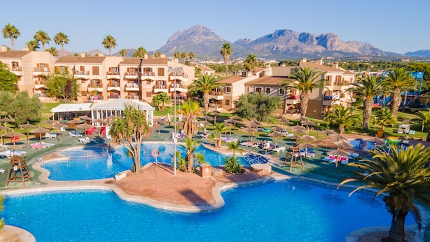 Ein Resort mit mehreren Schwimmbecken, Palmen und Bergblick.