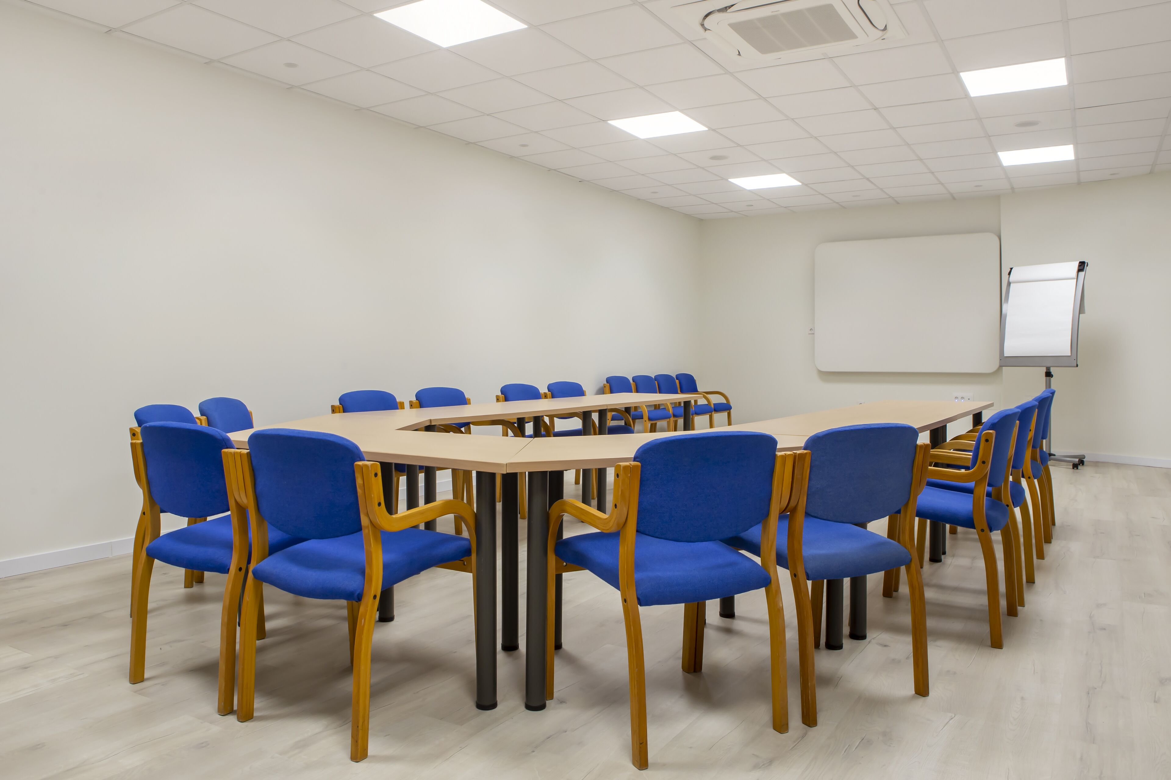 Una sala conferenze con un grande tavolo ovale circondato da sedie blu e in legno.