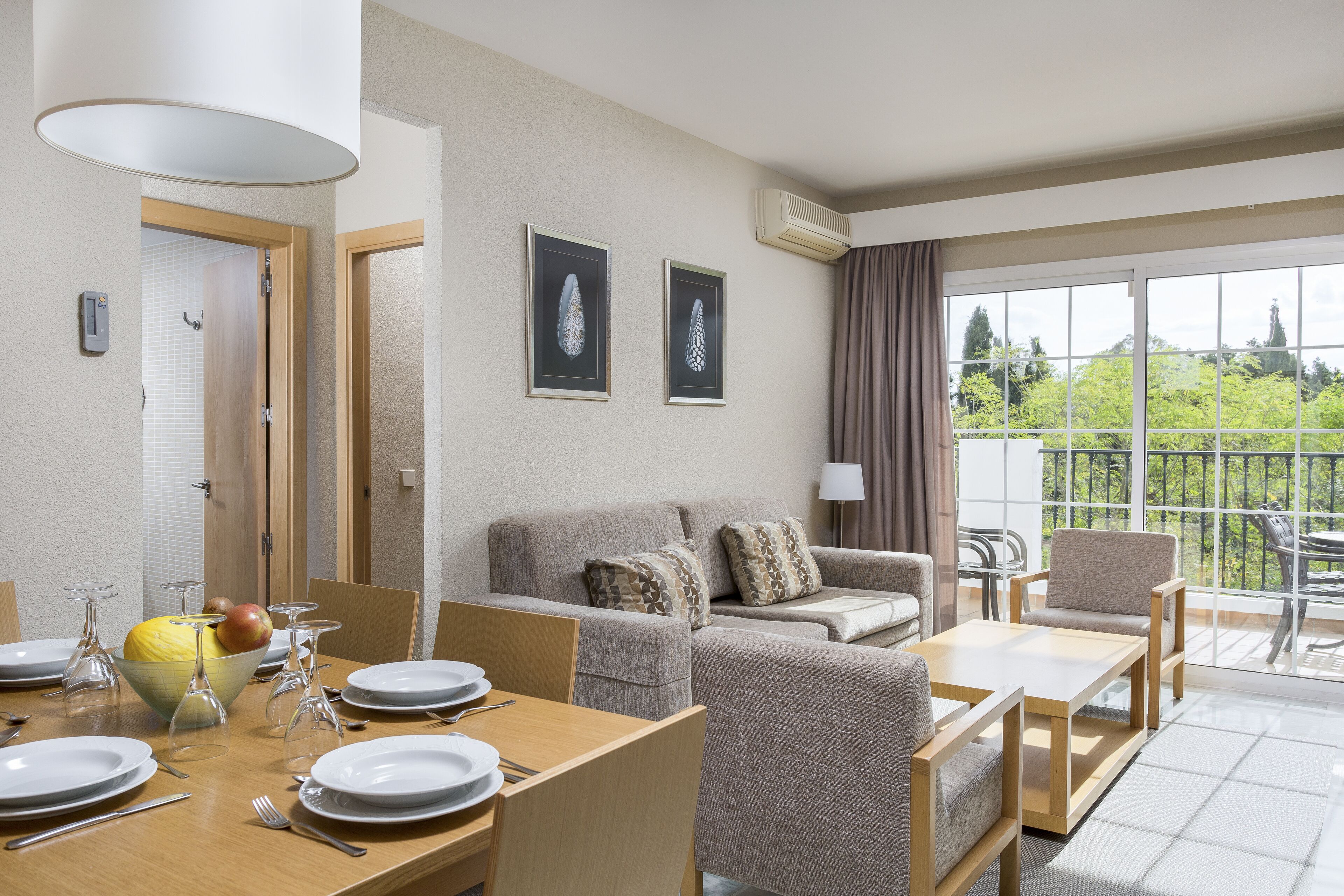 Una sala moderna con comedor, un conjunto de sofás y un balcón con vistas.