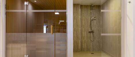 Un baño moderno con cabina de ducha de vidrio, techo de madera y zona de masajes a la vista.