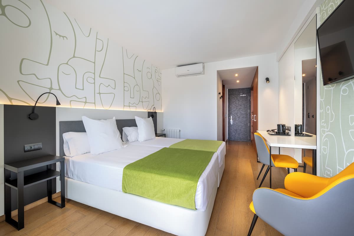 Una habitación de hotel moderna con una cama grande, un escritorio y una silla.
