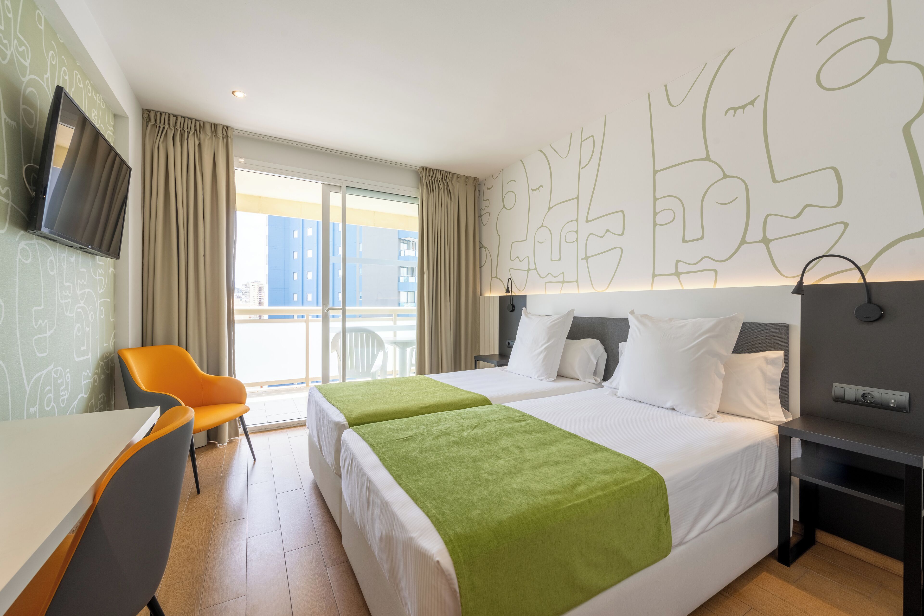 A hotel room with two beds, a TV, a desk, and a chair.
