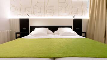 Une chambre d’hôtel avec un grand lit, deux tables de chevet, un climatiseur fixé au mur et une fenêtre avec des rideaux.