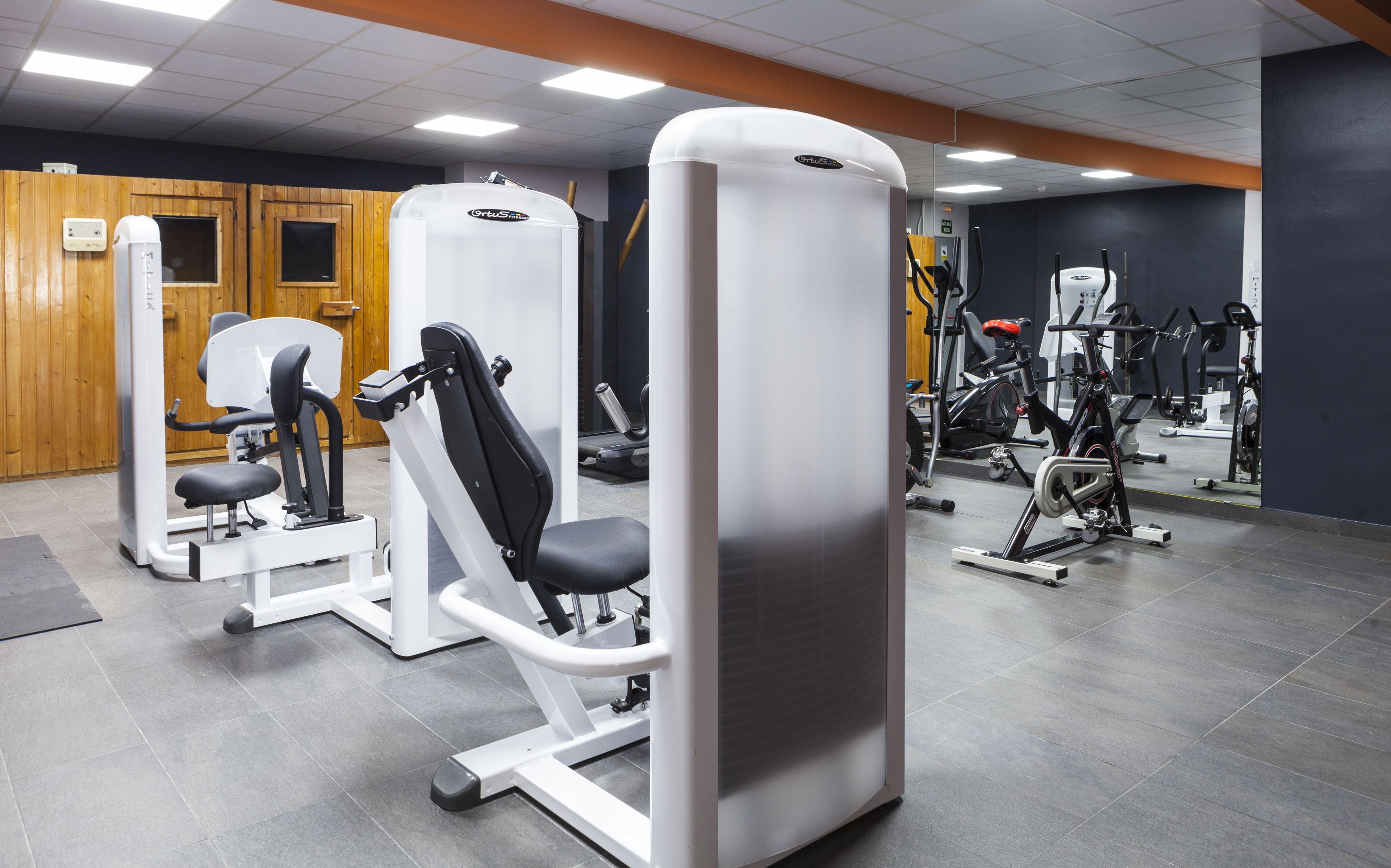 Un gimnasio con diversas máquinas de ejercicio, incluyendo una prensa de piernas y una prensa de pecho.