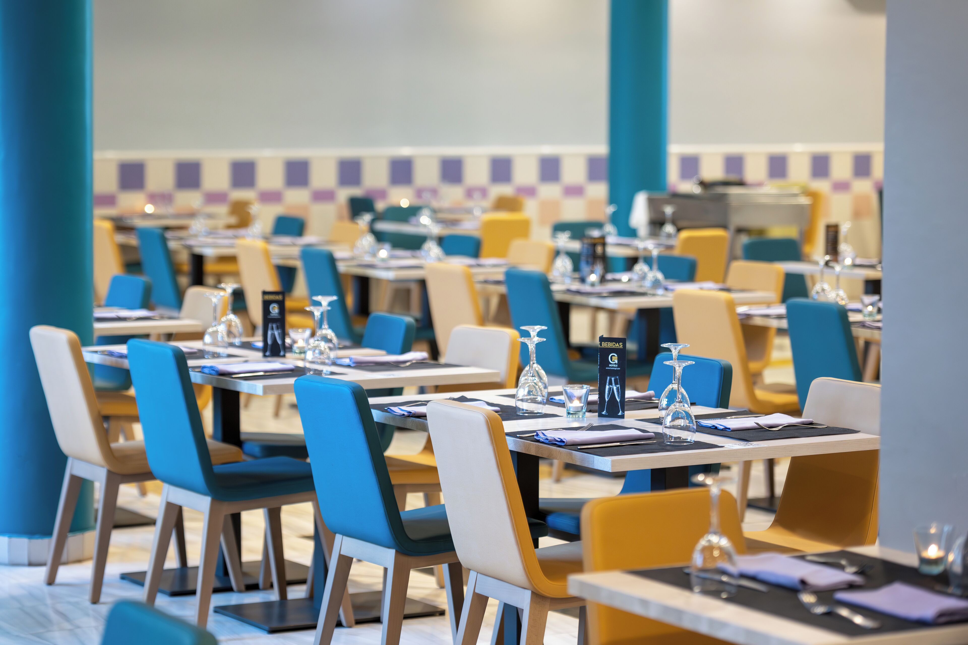 Un comedor con varias mesas y sillas, cada conjunto con cubiertos y cristalería.