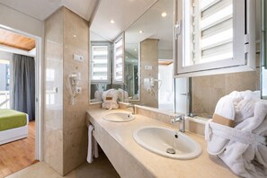 Un baño de hotel con dos lavamanos, un espejo grande y una zona de ducha.