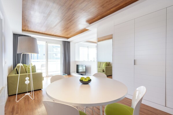 A modern living room with a round dining table, green sofa, and a television.