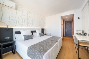 Una habitación de hotel moderna con una cama grande, una mesita de noche y un escritorio con una silla.