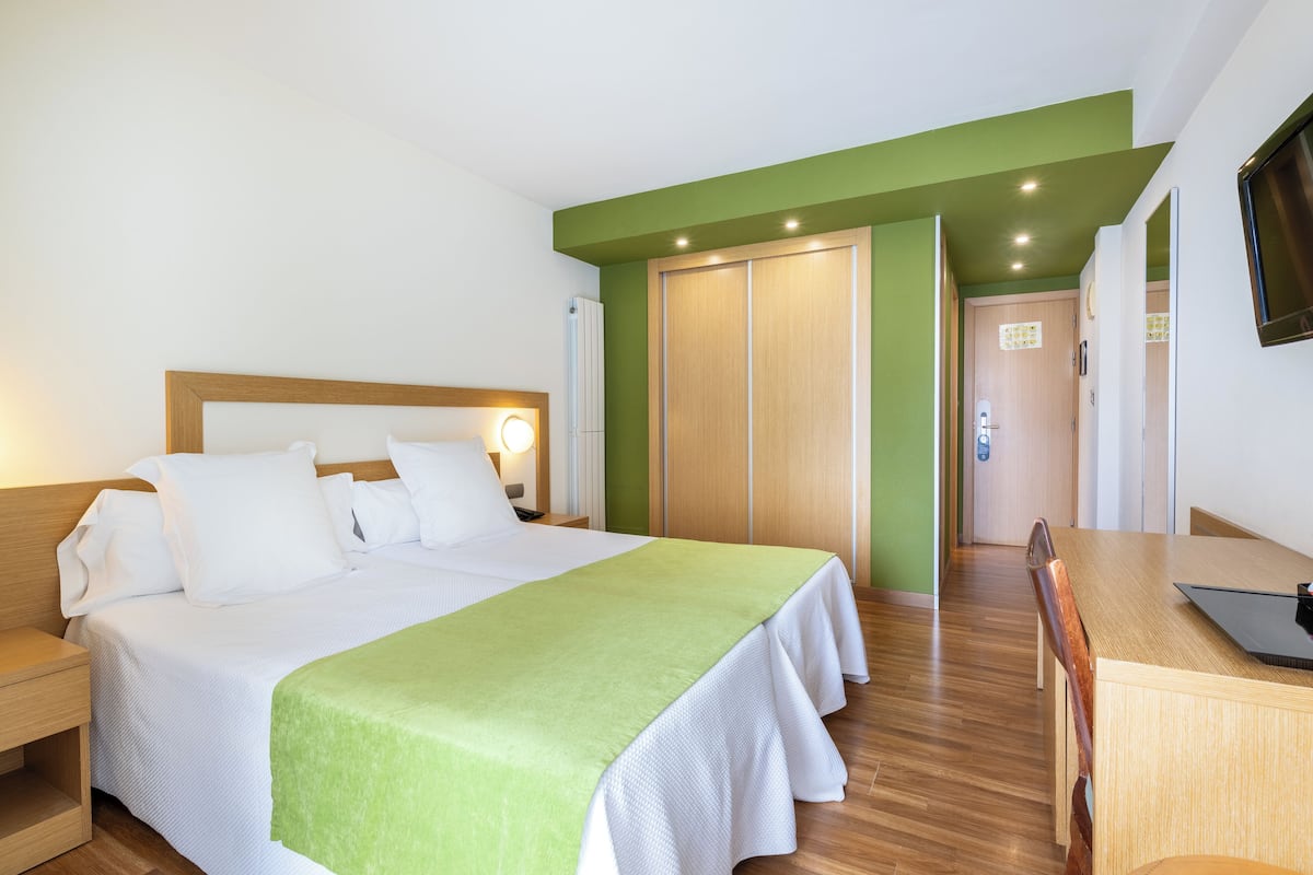 Una habitación de hotel con cama, mesita de noche y escritorio con silla.