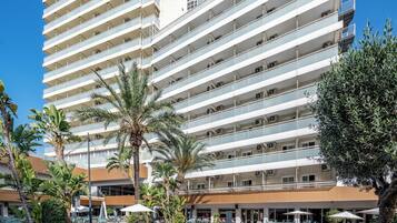 Un hotel con una amplia zona de piscina, varios balcones y palmeras.