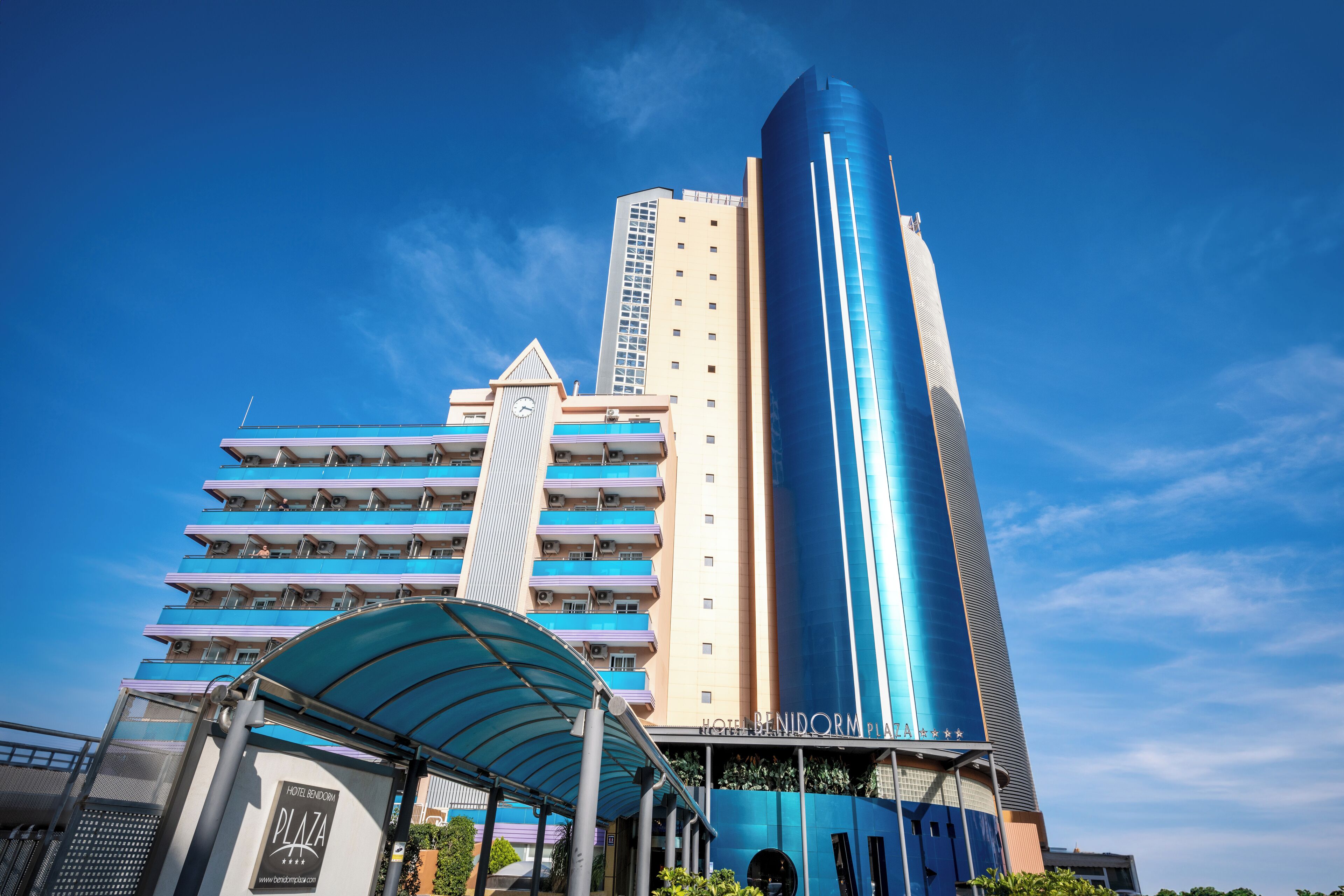 Un hotel de diseño moderno, con una destacada torre azul y una zona de acceso cubierta.