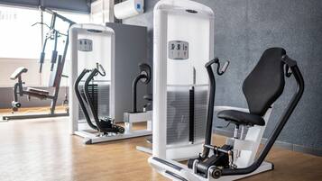Ein Fitnessstudio mit Cardiogeräten, Krafttrainingsgeräten und einem Rudergerät.