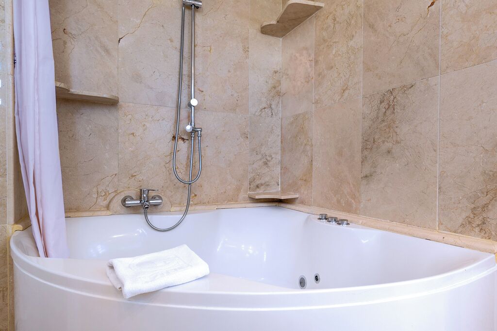 Un baño con bañera, ducha y paredes de mármol.