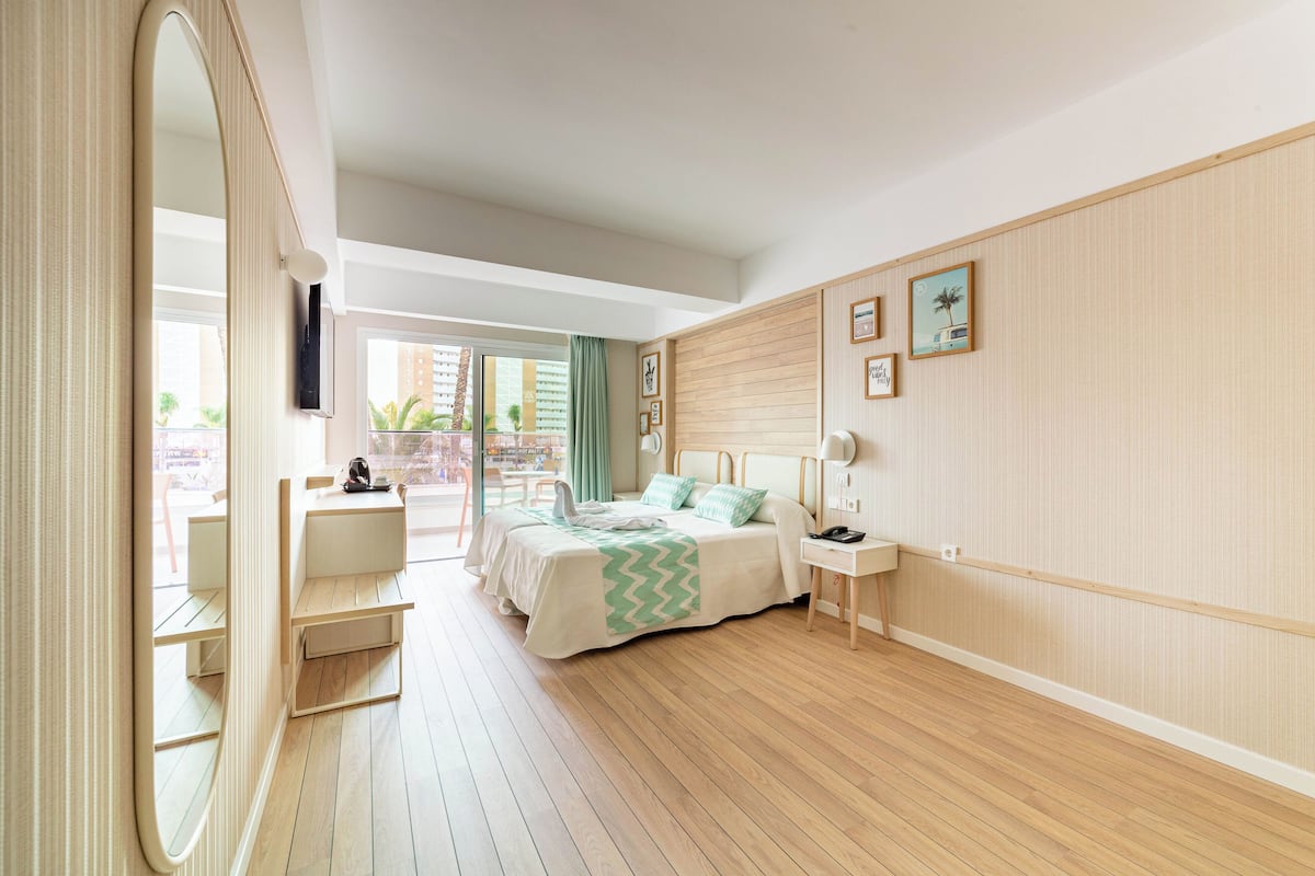 A modern bedroom with a bed, bedside table, and a large mirror.