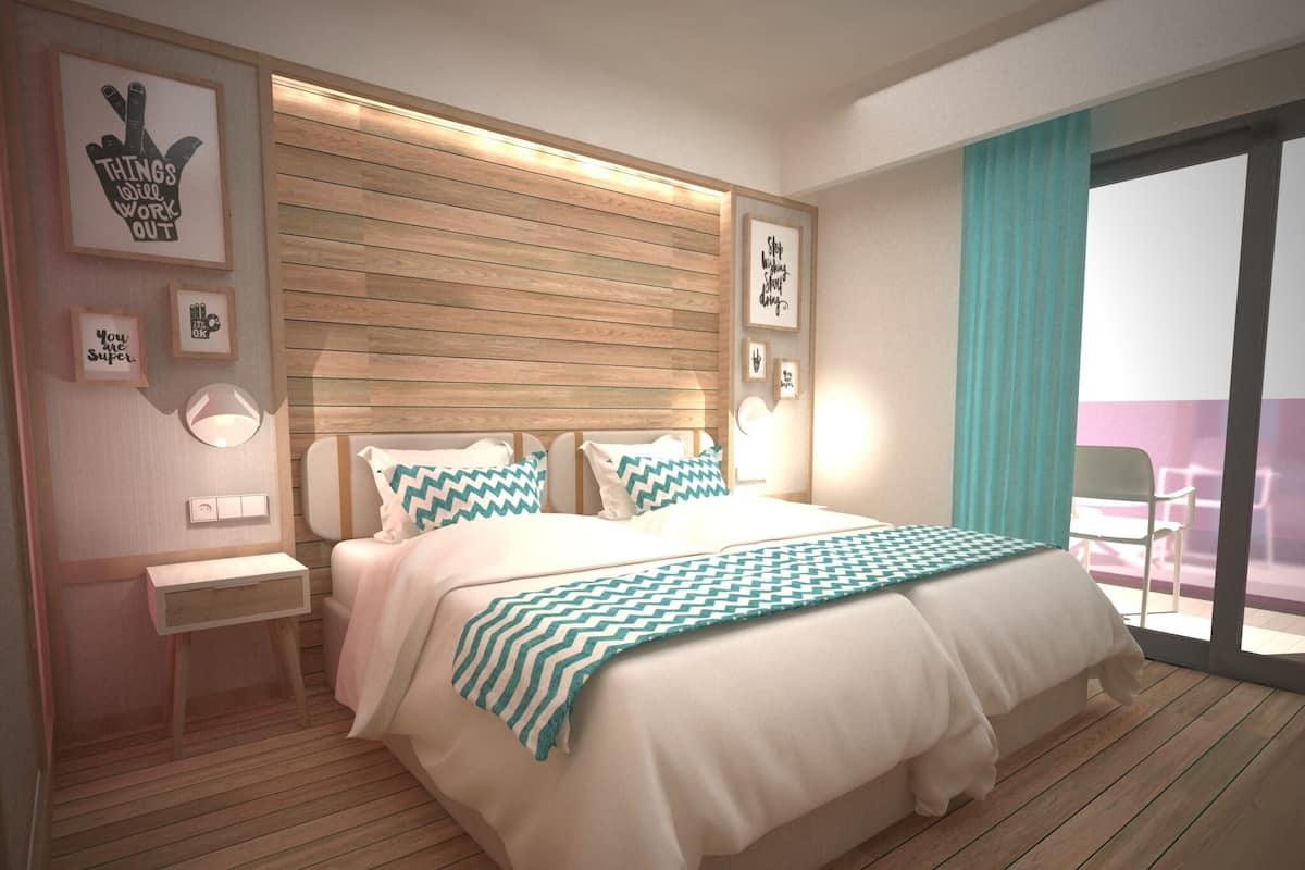 A modern bedroom with a wooden floor, a large bed with patterned pillows, bedside tables, and wall-mounted lighting.