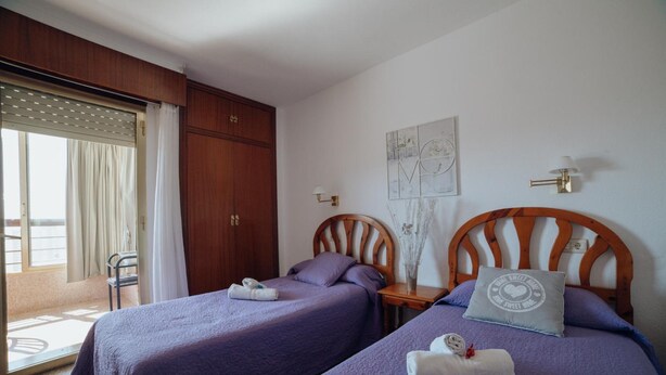 Una habitación con dos camas, un armario de madera, una mesita y una silla.