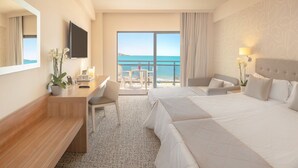 Habitación de hotel con una cama grande, un escritorio, una silla y vistas al mar.