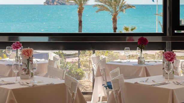 Mesa lista para comer con vista al mar y palmeras.