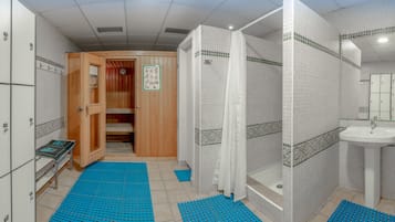 Une salle de bain avec une douche, un lavabo et une porte en bois donnant sur un vestiaire.