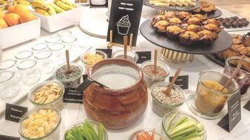 Un bufé con diferentes opciones de comida, entre ellas frutas, frutos secos y postres.