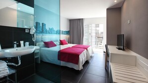 A modern hotel room with a large bed, a bathroom with a sink, and a city view. - Hotel Agua Azul - Adults Only (Benidorm)