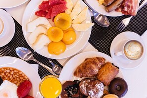 A breakfast spread with various dishes including eggs, beans, pastries, and fruits. - Hotel Agua Azul - Adults Only (Benidorm)