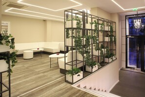 Eine moderne Lobby mit einem weißen Sofa, einem runden Tisch und einer begrünten Wand.