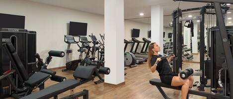 Un gimnasio con diversos equipos de ejercicio, incluyendo cintas de correr y máquinas de pesas.