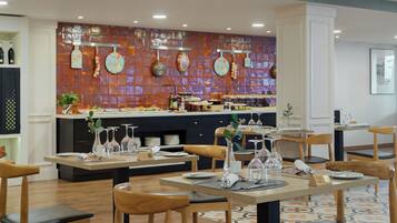 Un restaurante con mesas y sillas de madera, un salpicadero de azulejos y una zona de bufé al fondo.