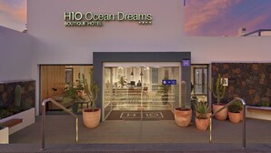 The entrance of H10 Ocean Dreams Boutique Hotel with a modern design, featuring a glass door, potted plants, and a clear view into the lobby area. - H10 Ocean Dreams Boutique Hotel - Adults Only (La Oliva)