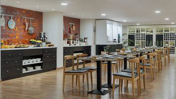 Un comedor moderno con mesas y sillas de madera, un mostrador de buffet con diversas opciones de comida y una exhibición de vinos.
