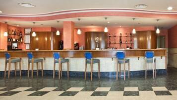 A bar area with a checkered floor, wooden bar counter, and blue chairs.