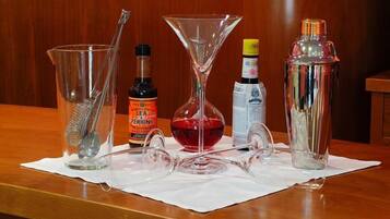 A bar setup with a cocktail shaker, a martini glass, a jigger, a bottle of Lea & Perrins Worcestershire sauce, a bottle of bitters, and a bottle of bitters.