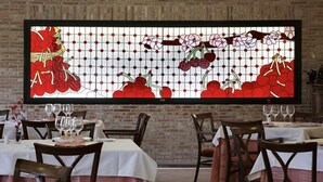 Un restaurante con mesas dispuestas para comer, una pared de ladrillo y un ventanal con diseños florales.