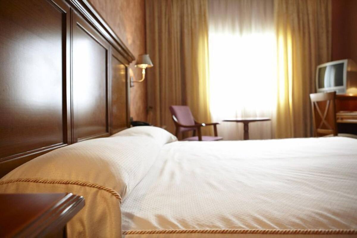 Une chambre d’hôtel avec un grand lit, un bureau avec une chaise, une télévision et une lampe.