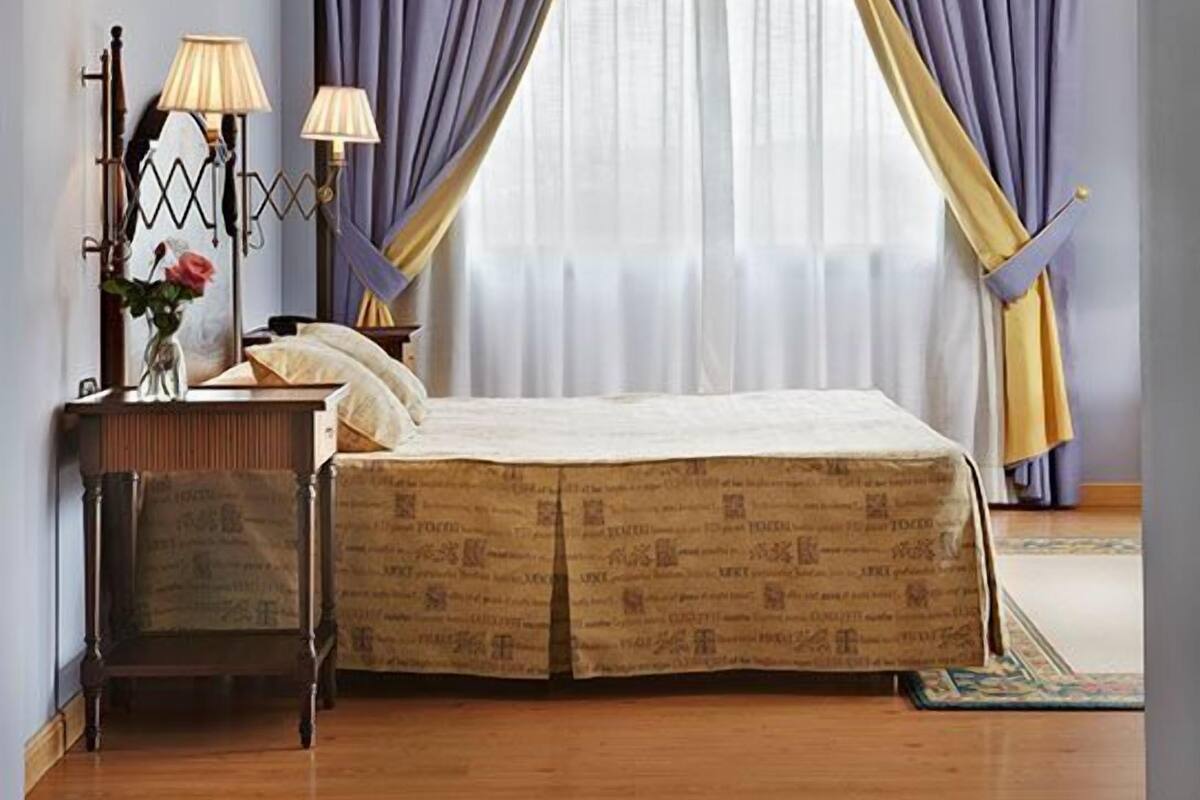 Une chambre à coucher avec un lit, des tables de chevet, des lampes et une fenêtre avec des rideaux.