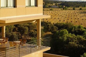 A building with a balcony overlooking a field of hay bales. - Hospedium Hotel Doña Mafalda de Castilla (Plasencia)