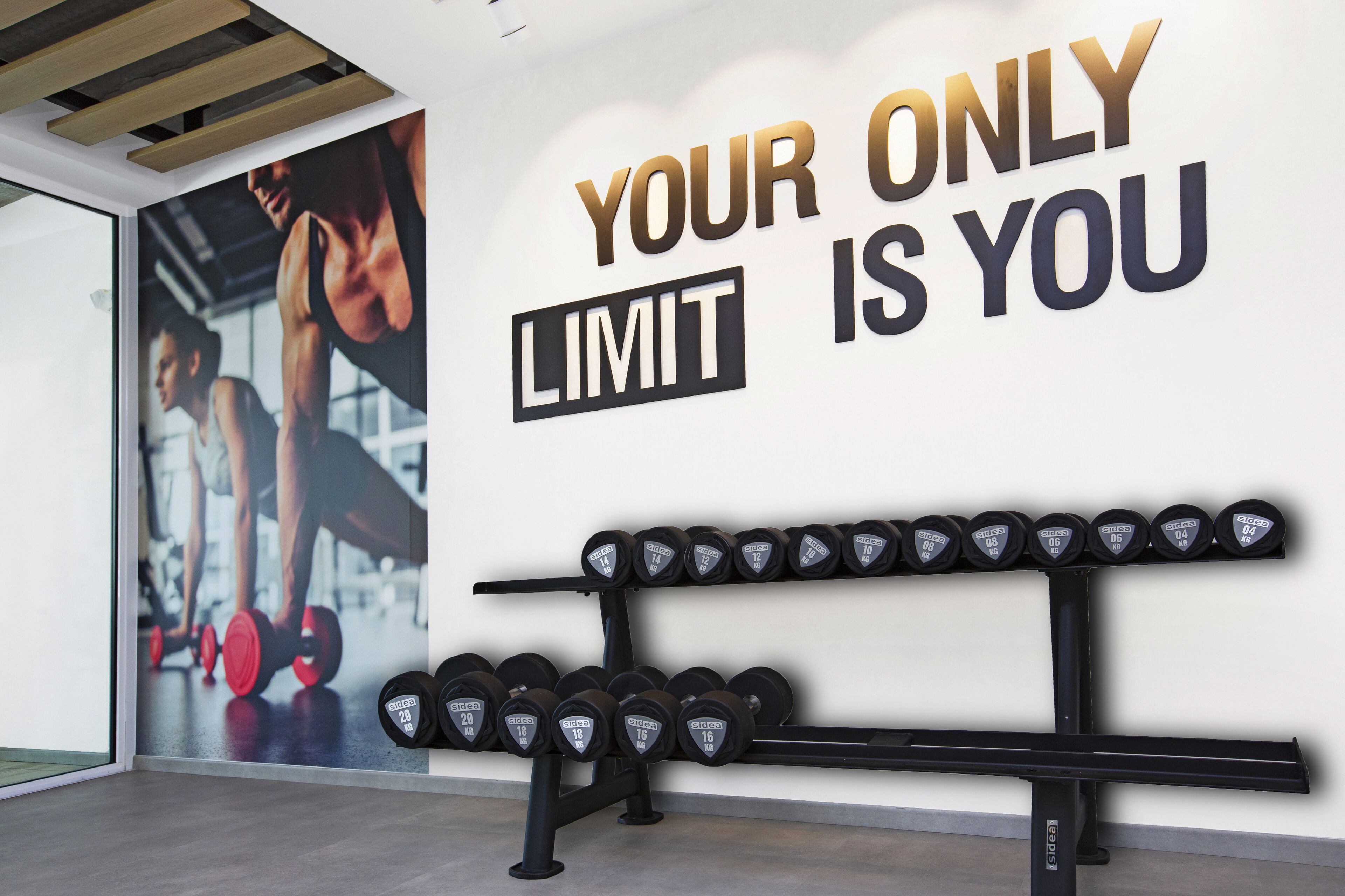 A gym with motivational wall text and a rack of dumbbells.