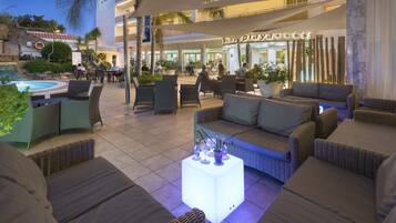 Un área de descanso al aire libre con piscina, asientos y un restaurante al fondo.