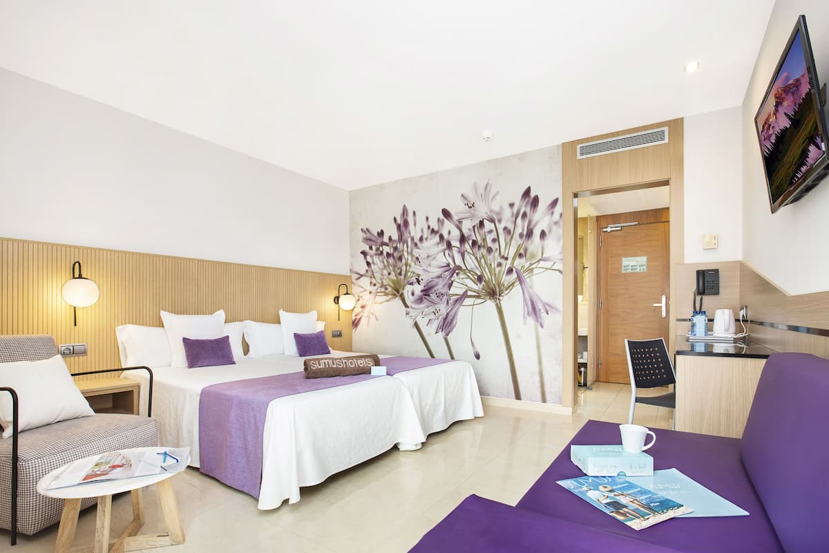 Una habitación de hotel con cama, sofá, una mesita y televisor.