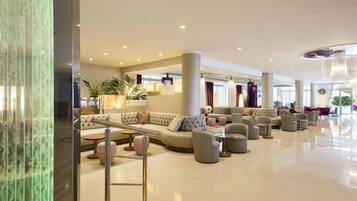 Een ruime lobby met een grote bank, meerdere fauteuils en een salontafel.