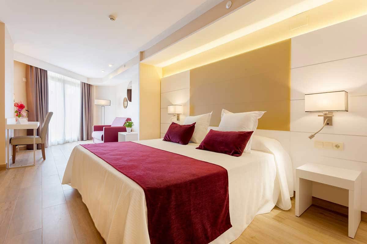 Una habitación de hotel moderna con una cama grande, mesitas de noche, un escritorio y una silla.